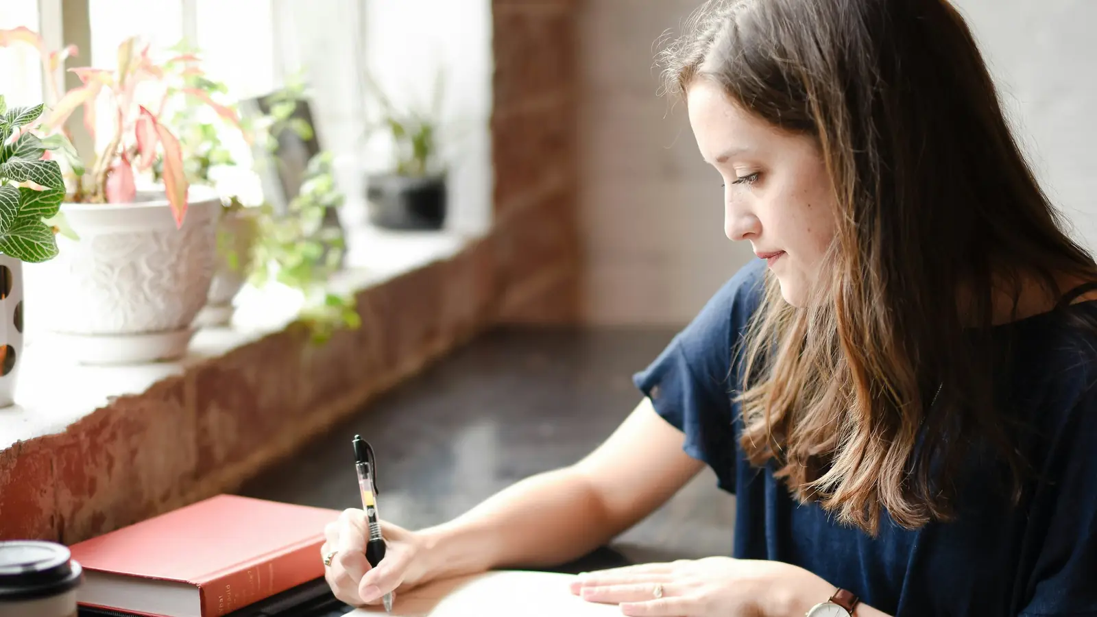 A woman writing in a journal at a table