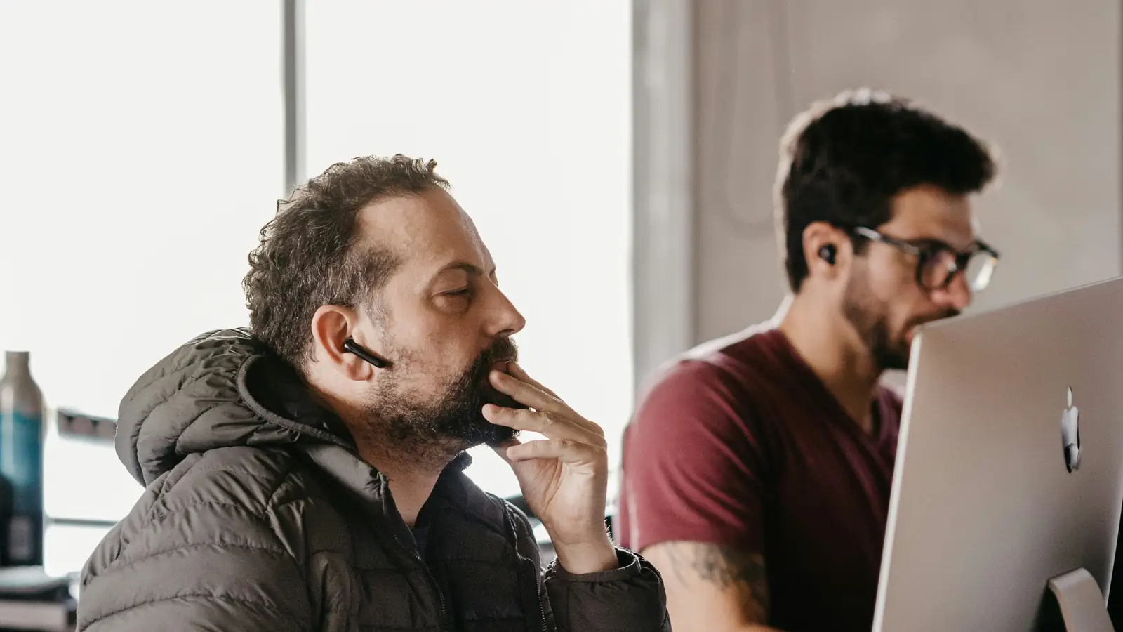 Two men at work, one tense with his hand over his mouth
