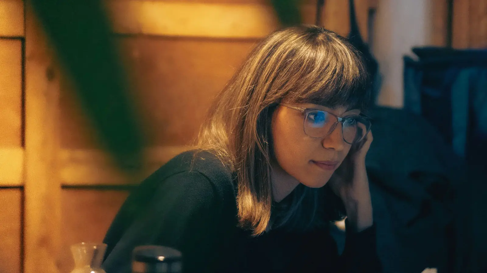 A woman at her desk at night, head resting in her hand