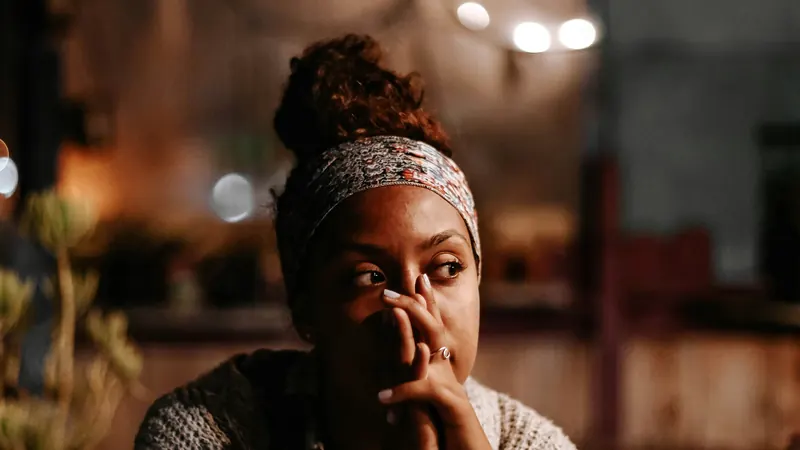 A woman lost in thought, her hand pressed to her mouth